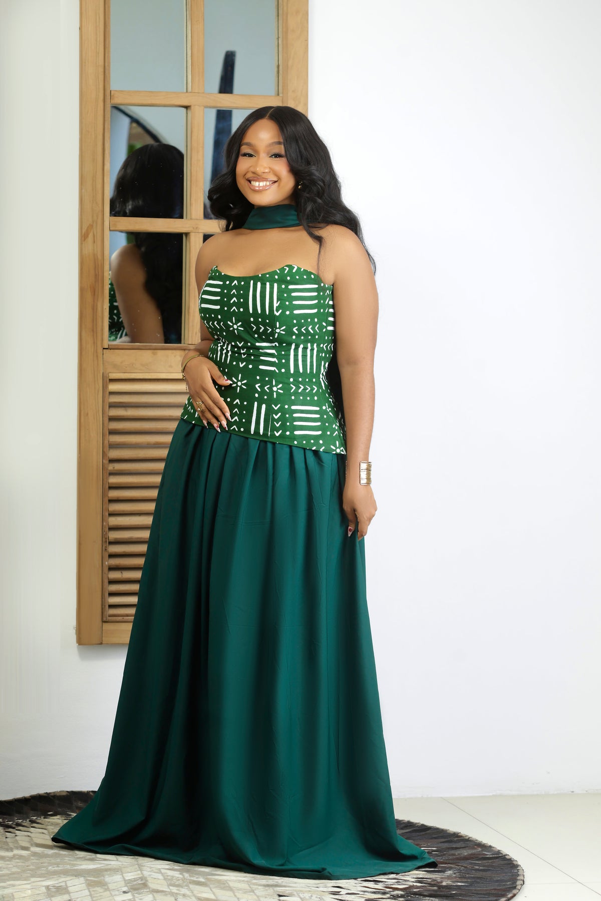 Full-length front view of the Miraya Set in deep emerald green — strapless African print corset top featuring white mud-cloth-inspired symbols, paired with a voluminous floor-length skirt and green choker scarf, styled with gold jewellery.